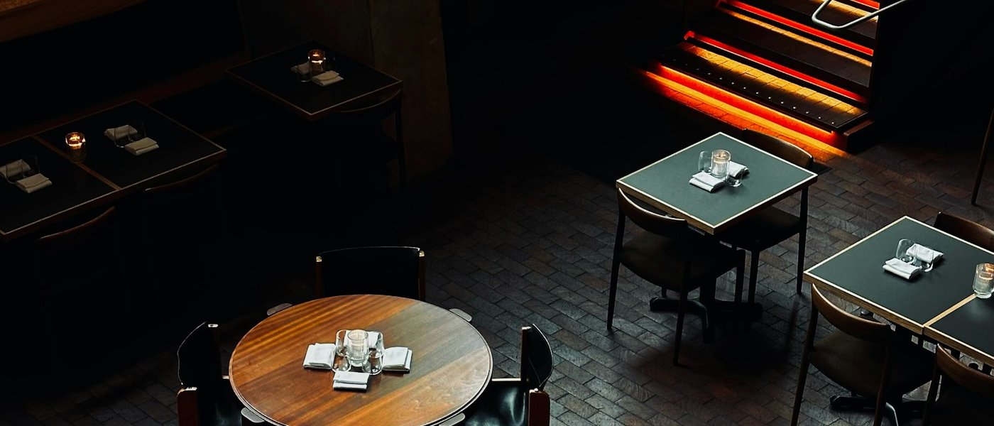Une salle de restaurant vue en plongée, ses tables disposées